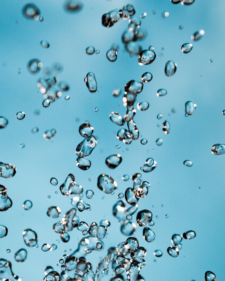 Vibrant image capturing water droplets suspended against a bright blue sky background.